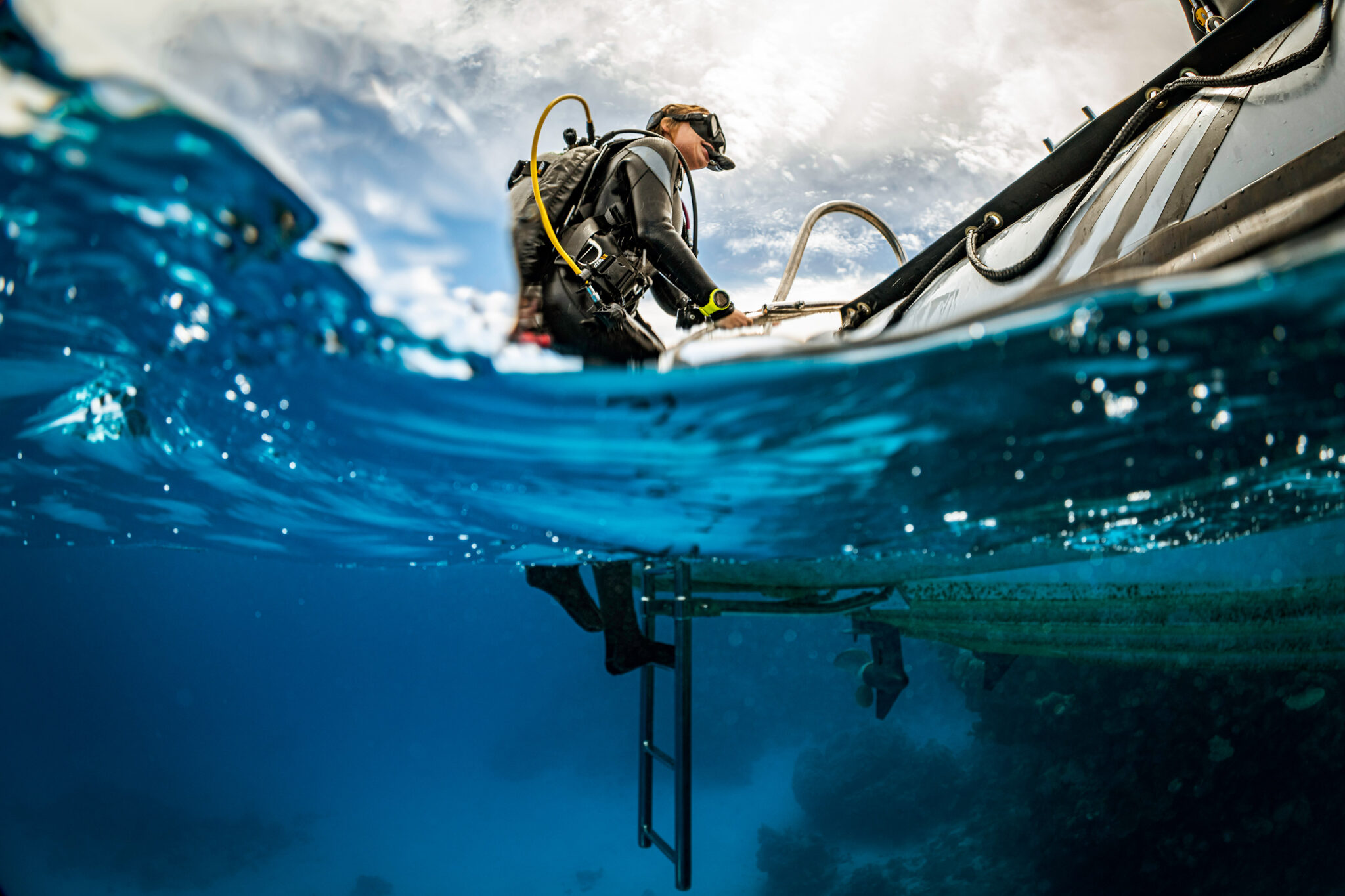 A scuba diver climbs out of the water using a boat ladder in the Red Sea Egypt