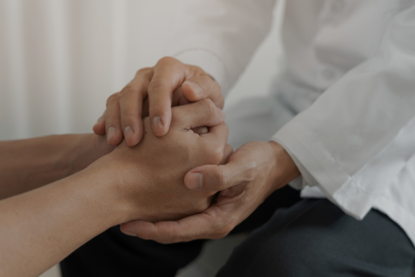 A person clasping the hands of another, supporting each other