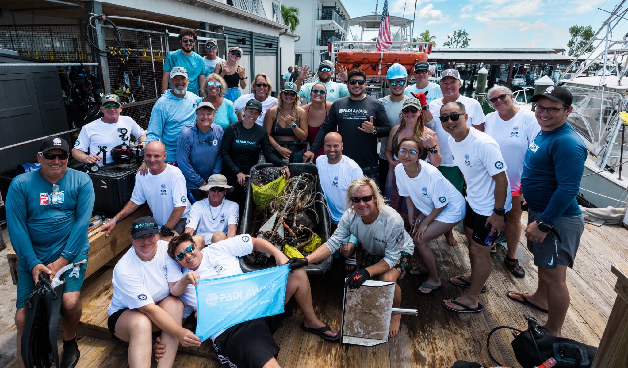 A group of divers in the Islamorada Dive Center showing off the trash they collected on a PADI AWARE Dive Against Debris dive