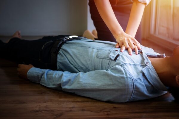 volunteer office woman use hand pump on chest for first aid emergency CPR on heart attack man unconscious, try to resuscitation patient man at work