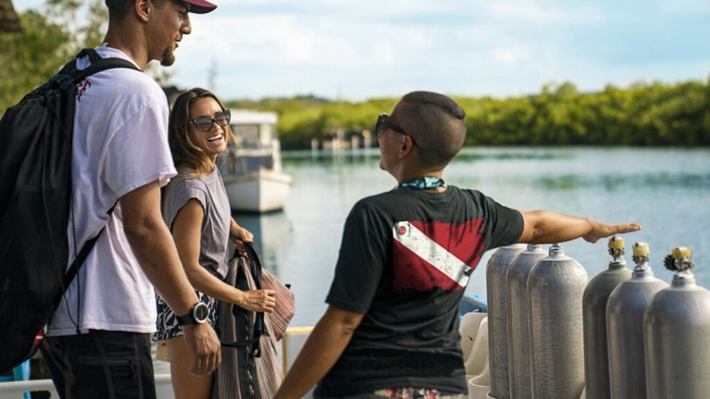 three scuba divers on a dock