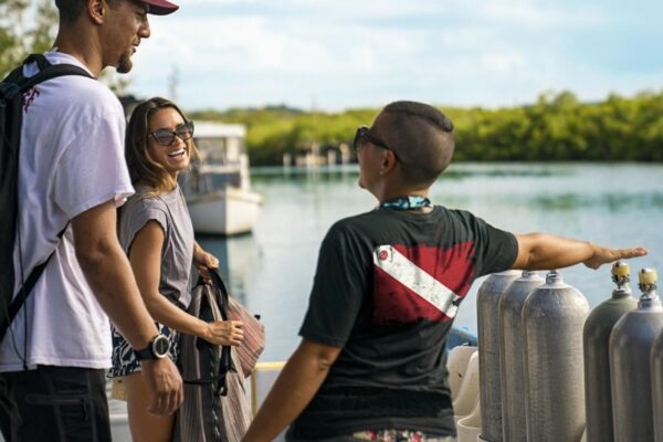 three scuba divers on a dock