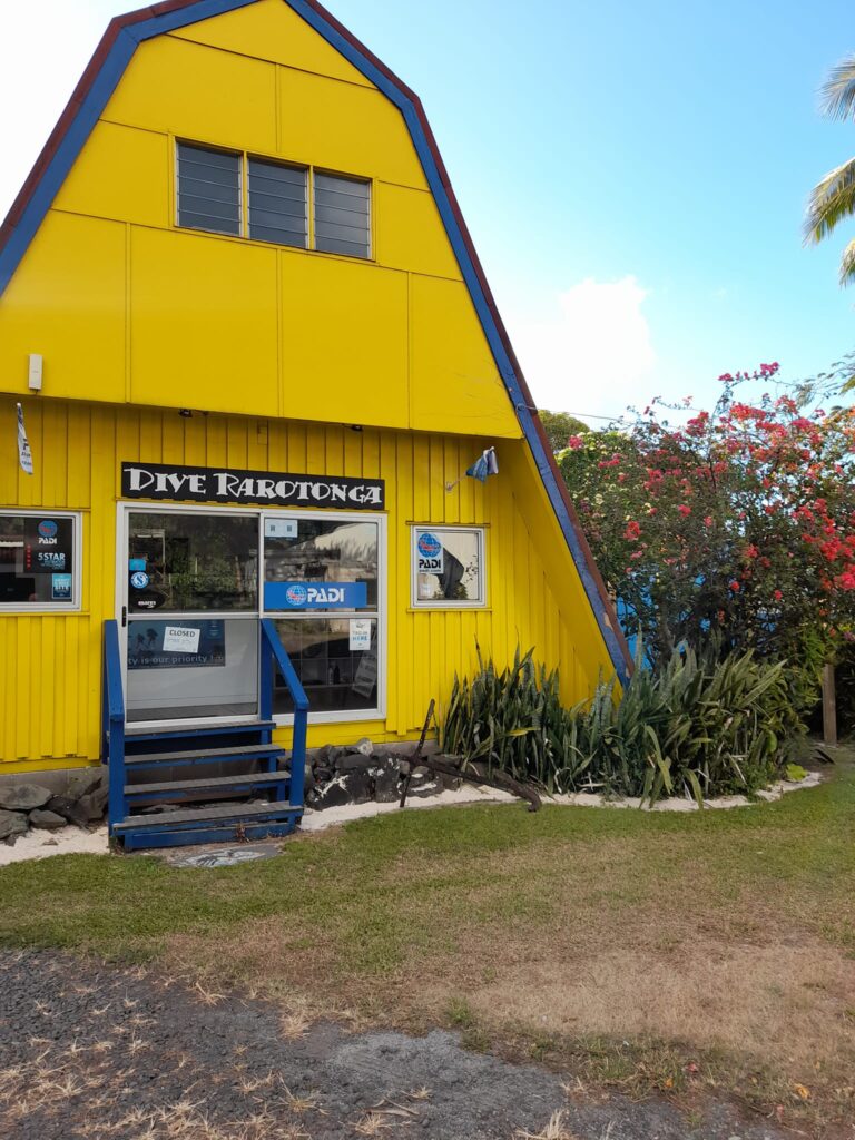 A bright yellow dive shop with a sign that days 'Dive Rarotonga'