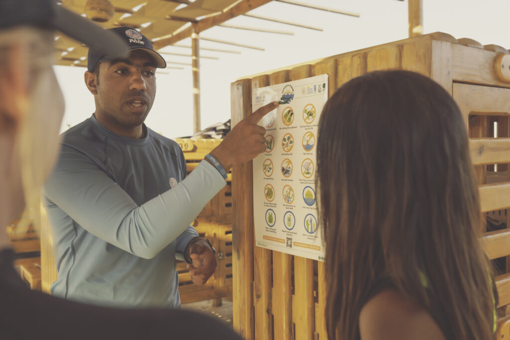 a man shows to other people the Green Fins sign in a dive center