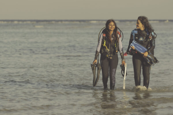 two women exit the water by shore after a dive in the Red Sea