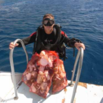 a technical diver gets on a boat with a bag of rubbish