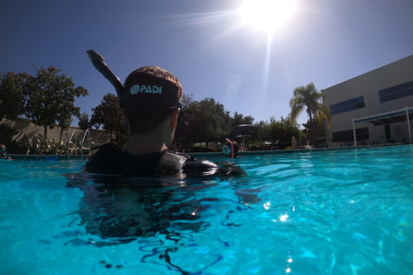 An open water diver student is neutrally buoyant in a swimming pools