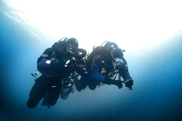 two divers descend using a rebreather