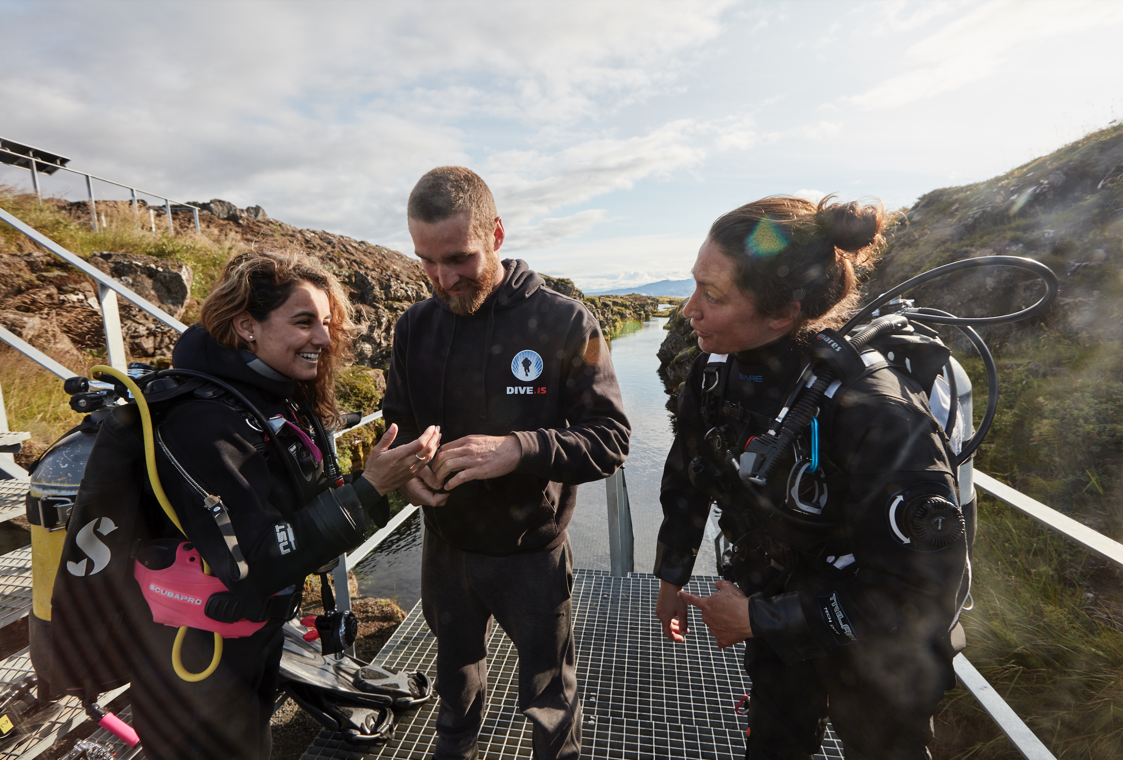 three divers discuss a dive before entering the water
