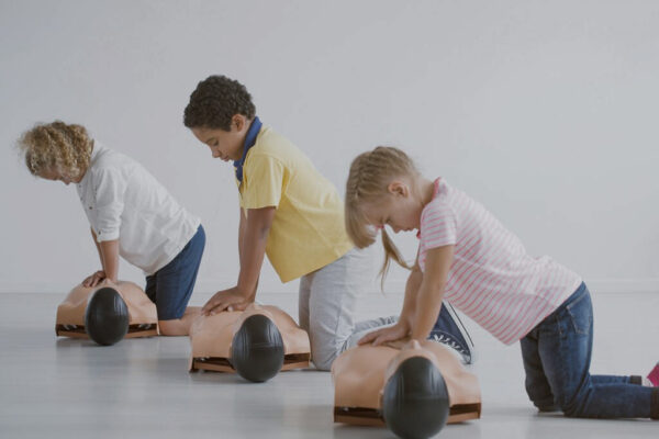 three children practice cpr on dummies