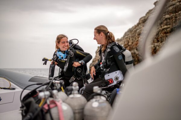 two female divers smiling together on a boat