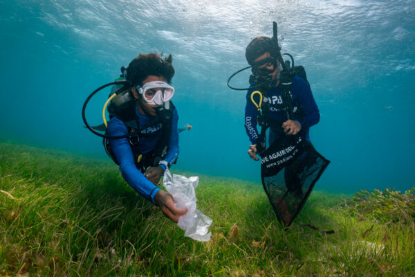 two divers complete a dive against debris by cleaning a seagrass dive site in the Maldives