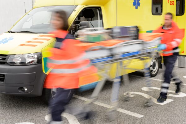 Emergency personnel maneuver a gurney in front of an ambulance