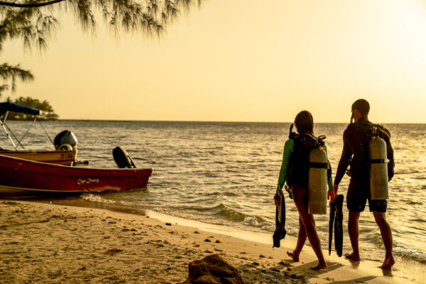 Two divers walking on the beach with their gear