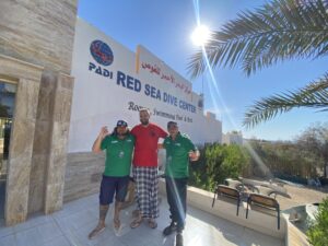 three people stand outside a PADI dive center in Aqaba, Jordan