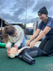 two women perform CPR on a CPR dummy as a part of Rescue Diver training