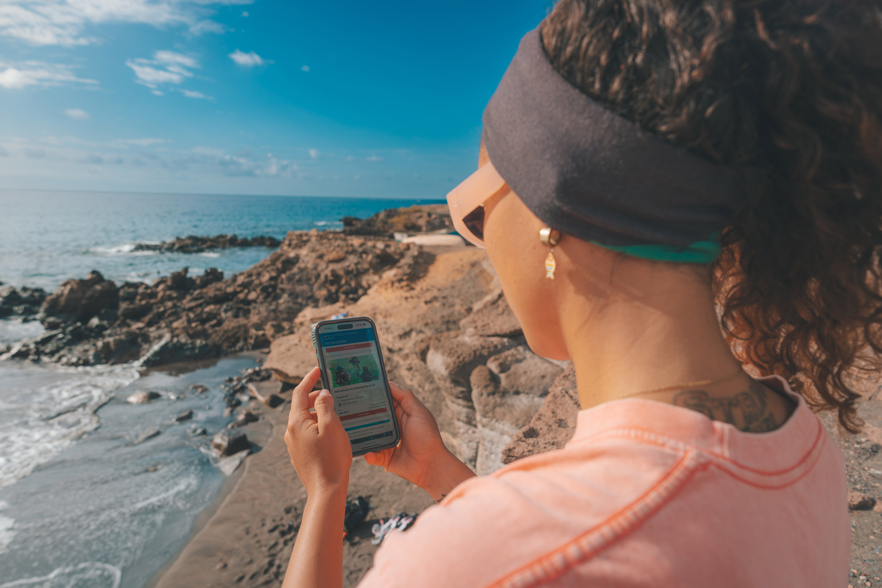 Una mujer mira su teléfono mientras está de pie en una playa junto al océano
