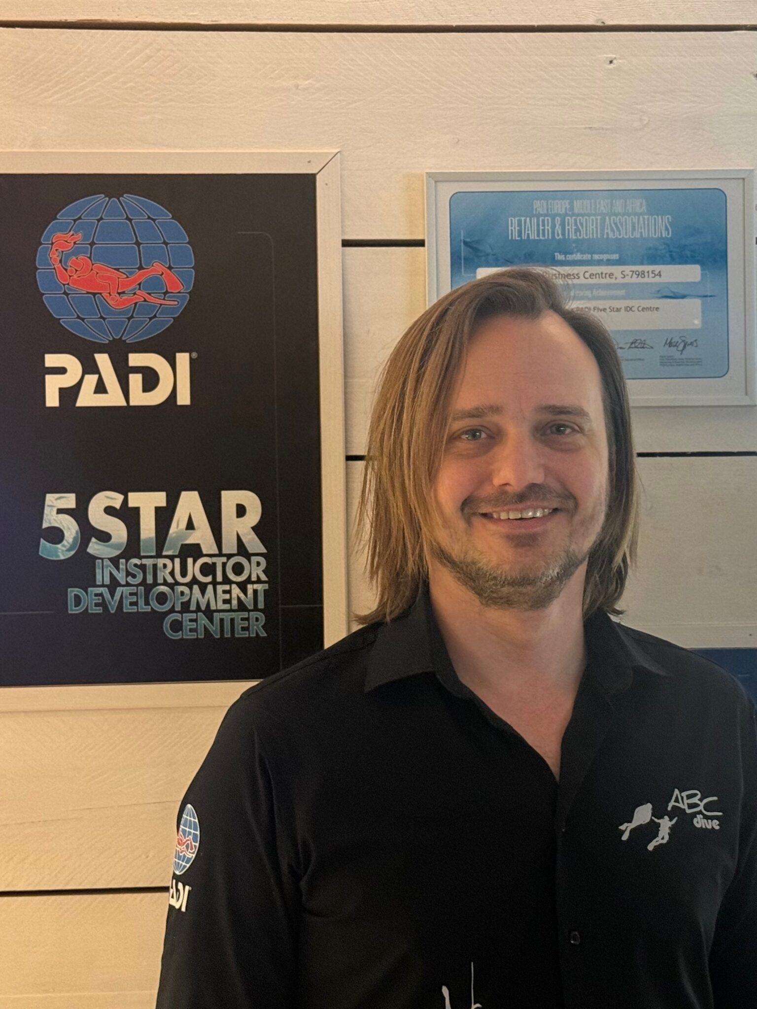 Portrait of a diver in a black shirt in front of a PADI 5 Star sign - winner of MSD Challenge 2025